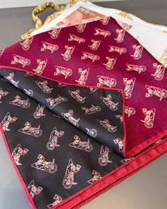 Detail of red and black silk scarf featuring golden carriage patterns and delicate hem