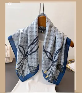 Détail d'un foulard en soie à motif géométrique avec imprimé pompon et finition bleu et blanc