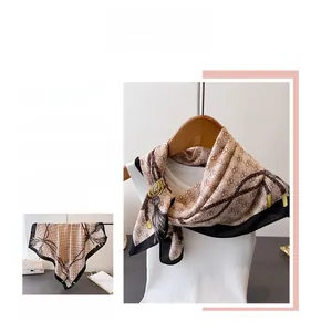 Détail d'un foulard en soie vintage champagne doré avec motifs de chaînes et imprimés géométriques