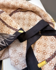 Gros plan détaillé d'un foulard en soie avec motifs monogrammes et bordure à chevrons
