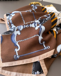 Detailed view of the herringbone texture and harness chain print on the brown scarf