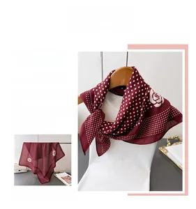 Detail of burgundy scarf with white polka dots and rose patterns on smooth satin fabric
