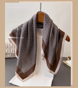 Detail of geometric circle chain print scarf draped on a wooden hanger with ivory border