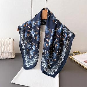 Floral navy blue silk scarf with vintage orange patterns draped on white knitwear background