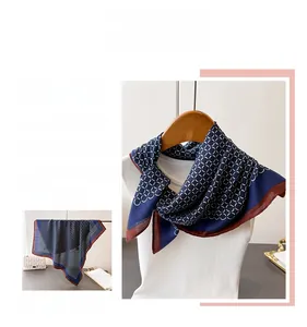 Detail of silk-feel scarf with geometric chain pattern and contrast red borders