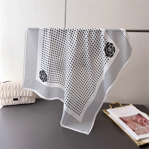Elegant polka dot square scarf with camellia print hanging on a sleek metal stand