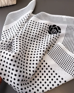 Detail shot of black and white polka dot scarf featuring elegant camellia flower pattern