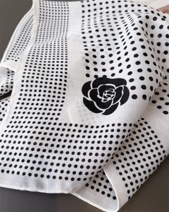Close-up of elegant silk-feel scarf featuring black camellia and polka dot patterns