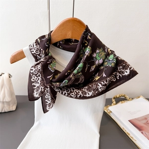 Navy floral square scarf with herringbone pattern draped on a white vest on a hanger