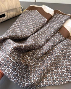 Detail of geometric chain print silk scarf with luxury texture and brown contrast borders
