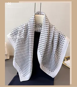 Detail of elegant black and white polka dot silk-feel square scarf on a mannequin