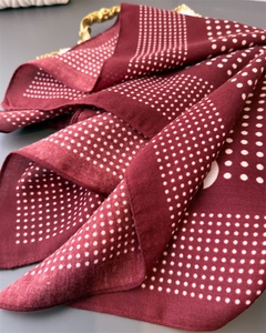 Close-up of wine red herringbone scarf with white polka dots and elegant golden accent