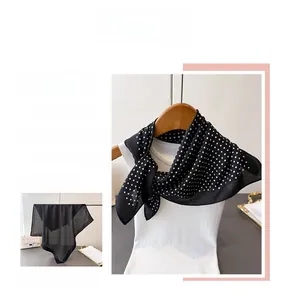Close-up of lightweight black silk scarf with classic white polka dot pattern on hanger
