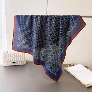 Blue geometric chain link square scarf with brick red border shown in a lifestyle setting