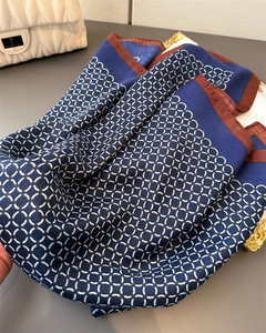 Detail of geometric navy blue silk scarf with brown border on a metallic tray
