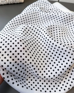 Close-up of classic black polka dot pattern on white twill fabric with soft texture