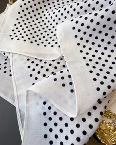 Macro detail of white herringbone weave fabric with classic black polka dots and fine edges