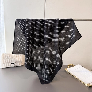 Close-up of black polka dot silk scarf draped elegantly over a metallic display bar