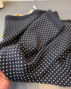 Detailed macro view of black polka dot scarf featuring textured fabric and hemmed edges