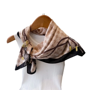 Élégant foulard beige en soie avec motifs de chaînes et logo sur un gilet blanc