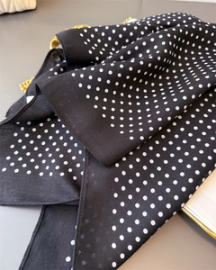Close-up of black polka dot scarf with herringbone texture and elegant gold chain detail