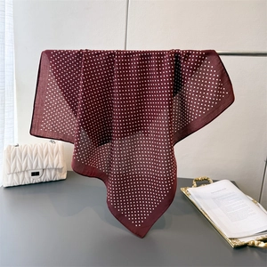 Detail of burgundy polka dot square scarf with premium rolled edges on a metal hanger