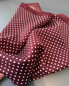 Detail of herringbone texture and white polka dots on a burgundy satin silk scarf