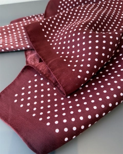 Detailed close-up of herringbone texture and white polka dots on burgundy silk scarf
