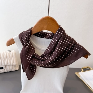 Detailed view of coffee brown polka dot silk scarf styled on a white tank top