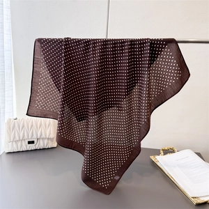 Detail of lightweight brown polka dot square scarf showing drape and texture