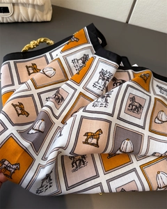 Vue détaillée d'un foulard en soie avec motifs équestres et blocs de couleur orange vifs
