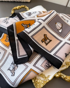 Détail d'un foulard équestre en coton et lin avec motifs de chevaux et carreaux sur un plateau