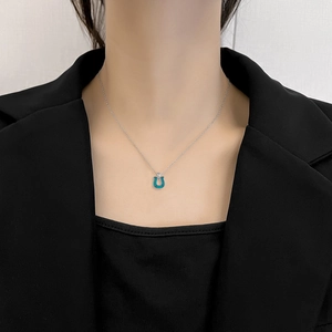 Minimalist silver horseshoe necklace with turquoise pendant worn by a model