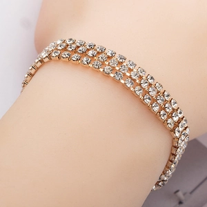 Dettaglio macro di bracciale tennis dorato a tre file con zirconi trasparenti incastonati