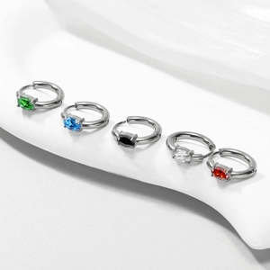 Close-up of five huggie earrings with colorful gemstones on white silk background