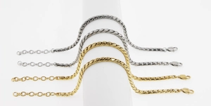 Bracelets gourmettes plates dorés et argentés sur un support à bijoux blanc poli