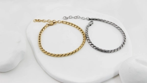 Détail des bracelets chaîne serpent plats en or et argent sur support géométrique