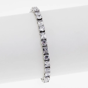 Silver tennis bracelet with alternating baguette and round cut stones on a white stand