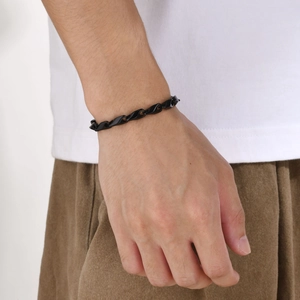 Détail d'un bracelet en acier titane noir à maillons torsadés porté au poignet masculin