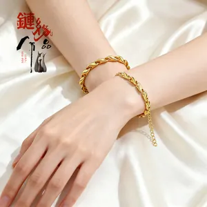 Détail d'un bracelet doré à maillons torsadés porté sur fond de tissu en soie blanche