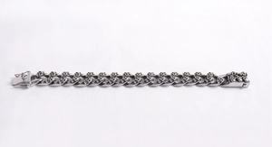 Macro detail of gothic stainless steel Cuban chain bracelet with double skull link design