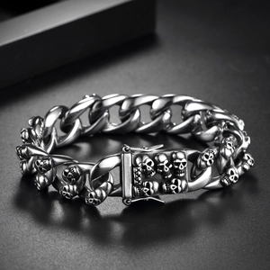 Detail of vintage Cuban link bracelet with 3D skull charms in aged stainless steel