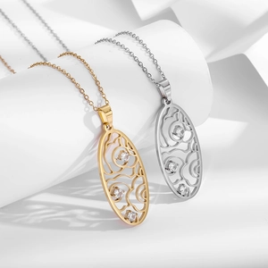 Detail of gold and silver hollow oval pendants with zircon stones on white display