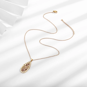 Detailed view of a gold waterdrop pendant with intricate hollow patterns and red zircons