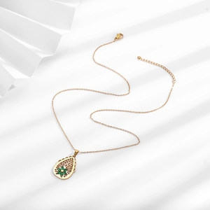Detail of gold hollow teardrop pendant necklace with green zircon flower center
