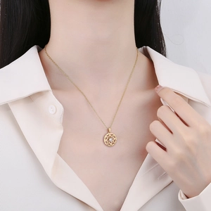 Close-up of golden hollow pendant necklace on model wearing white shirt