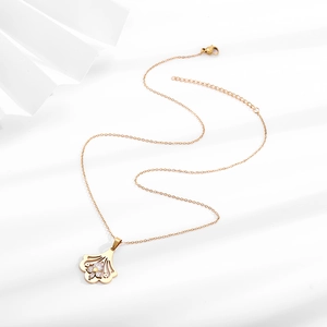 Elegant gold ginkgo leaf necklace with floral zircon inlay on a white artistic background