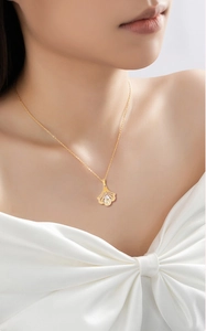 Close-up of golden ginkgo leaf necklace with three sparkling crystals on a model