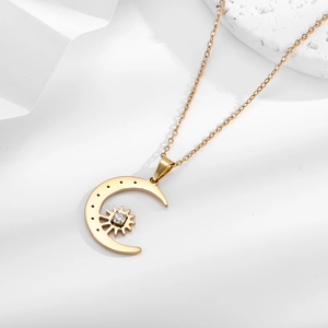 Macro detail of gold crescent moon pendant with sun inlay and sparkling zircon stone