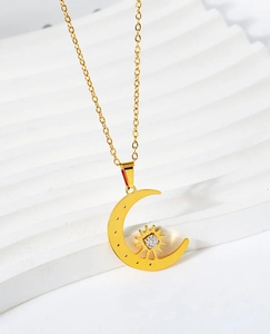 Detail of gold star and crescent moon necklace with sparkling zirconia on stone pedestal